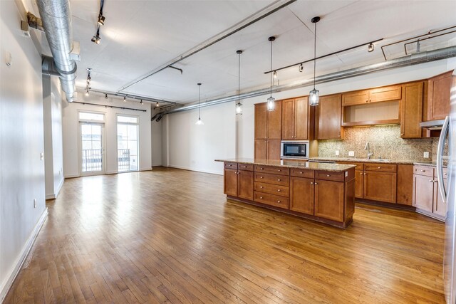 1616 Fountain View Dr Unit 202, Houston, TX 77057 - kitchen with rail lighting, a kitchen island, hardwood / wood-style floors, brown cabinetry, and decorative backsplash
