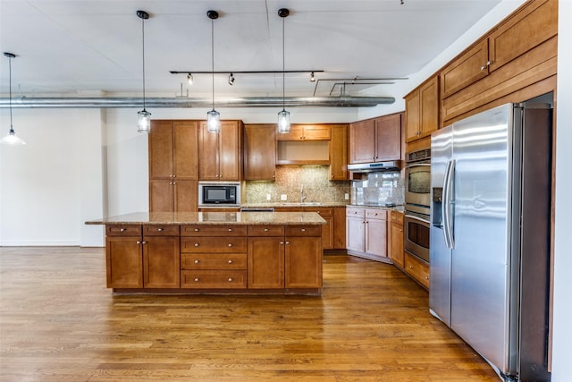 1616 Fountain View Dr Unit 202, Houston, TX 77057 - kitchen with appliances with stainless steel finishes, a center island, wood finished floors, and brown cabinetry