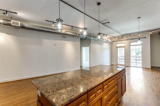 1616 Fountain View Dr Unit 202, Houston, TX 77057 - kitchen featuring rail lighting, open floor plan, brown cabinets, and light wood-type flooring
