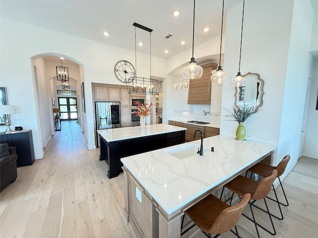 31306 Crescent Hill Dr, Fulshear, TX 77441 - kitchen featuring arched walkways, stainless steel refrigerator with ice dispenser, gas cooktop, a center island, and light wood-type flooring