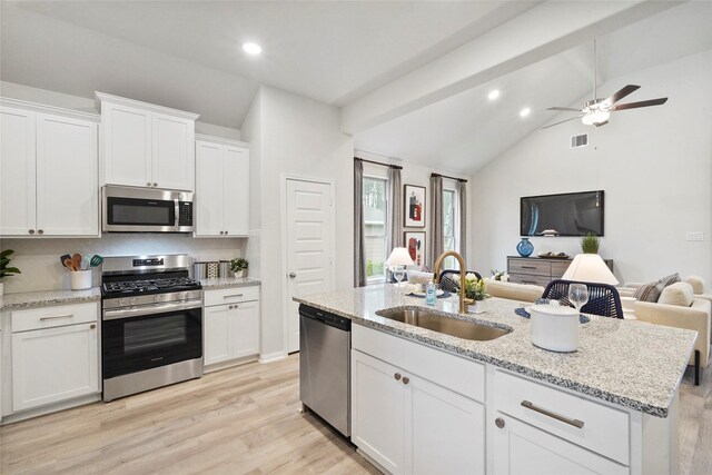 506 Fay Ct, Dayton, TX 77535 - kitchen featuring stainless steel appliances, lofted ceiling, open floor plan, white cabinets, and light wood-type flooring