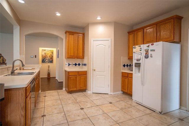 9434 Barretts Glen Ct, Houston, TX 77065 - kitchen with white fridge with ice dispenser, arched walkways, brown cabinets, dishwasher, and recessed lighting