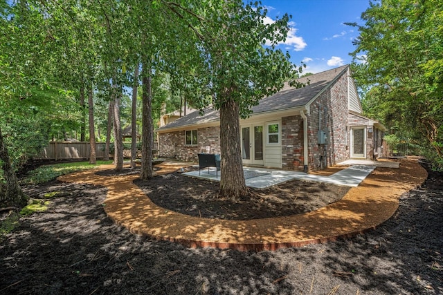 163 W Village Knoll Cir, The Woodlands, TX 77381 - back of property with french doors, a patio area, roof with shingles, and brick siding