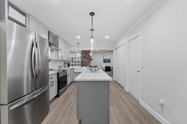 163 W Village Knoll Cir, The Woodlands, TX 77381 - kitchen with appliances with stainless steel finishes, wall chimney exhaust hood, a center island, gray cabinetry, and ornamental molding