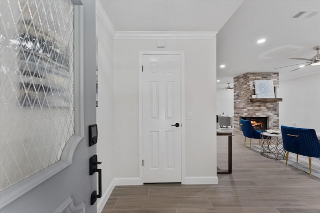 163 W Village Knoll Cir, The Woodlands, TX 77381 - entrance foyer featuring ceiling fan, a brick fireplace, crown molding, wood finished floors, and recessed lighting
