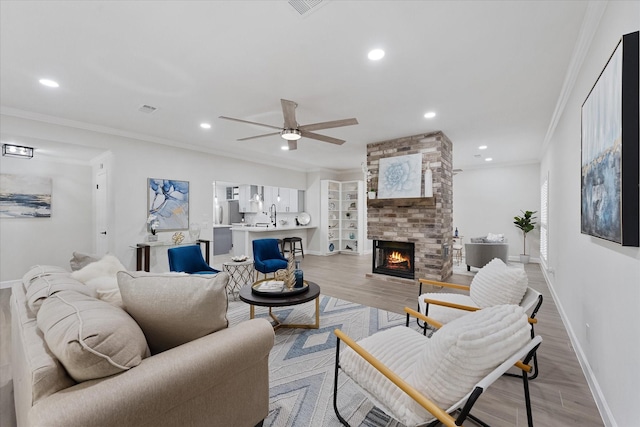 163 W Village Knoll Cir, The Woodlands, TX 77381 - living area with light wood-style floors, a ceiling fan, a fireplace, recessed lighting, and crown molding