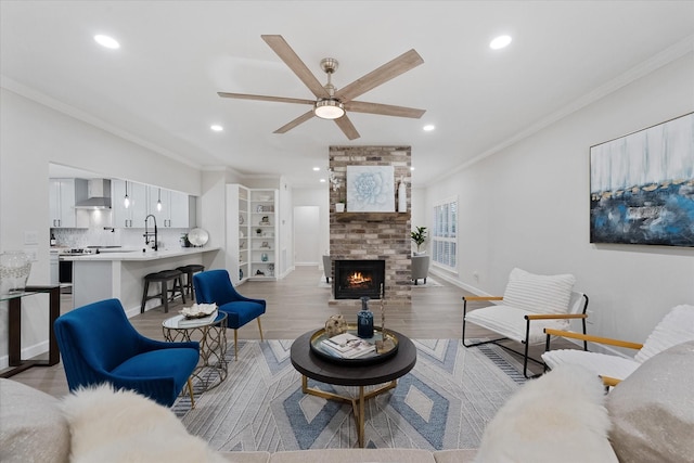 163 W Village Knoll Cir, The Woodlands, TX 77381 - living room featuring light wood-type flooring, ornamental molding, recessed lighting, ceiling fan, and a brick fireplace