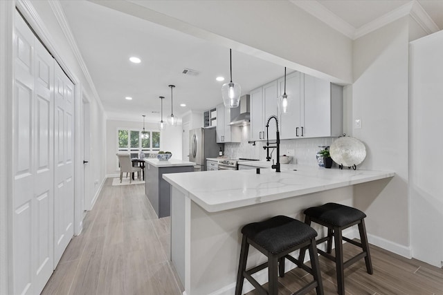 163 W Village Knoll Cir, The Woodlands, TX 77381 - kitchen featuring freestanding refrigerator, wall chimney exhaust hood, crown molding, a kitchen island, and recessed lighting