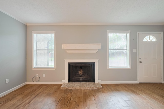 6452 Kentwick Dr, Houston, TX 77084 - unfurnished living room featuring wood-type flooring, ornamental molding, a fireplace with raised hearth, plenty of natural light, and a textured ceiling
