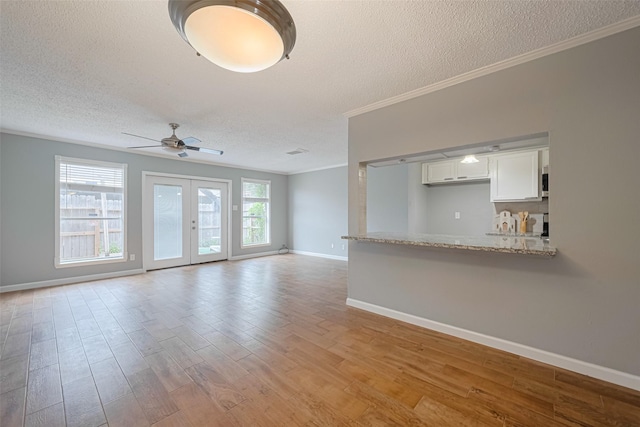 6452 Kentwick Dr, Houston, TX 77084 - unfurnished living room featuring a textured ceiling, ornamental molding, light wood-style flooring, ceiling fan, and french doors