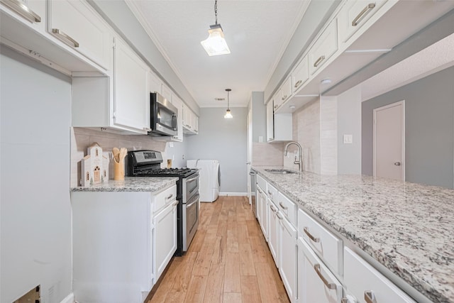 6452 Kentwick Dr, Houston, TX 77084 - kitchen featuring stainless steel appliances, washing machine and clothes dryer, ornamental molding, decorative backsplash, and white cabinetry
