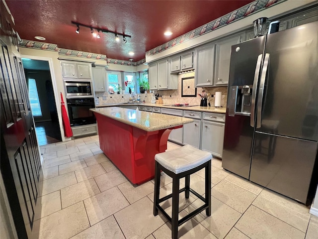 51 S Trillium Ct, Lake Jackson, TX 77566 - kitchen featuring refrigerator with ice dispenser, oven, stainless steel microwave, decorative backsplash, and a textured ceiling