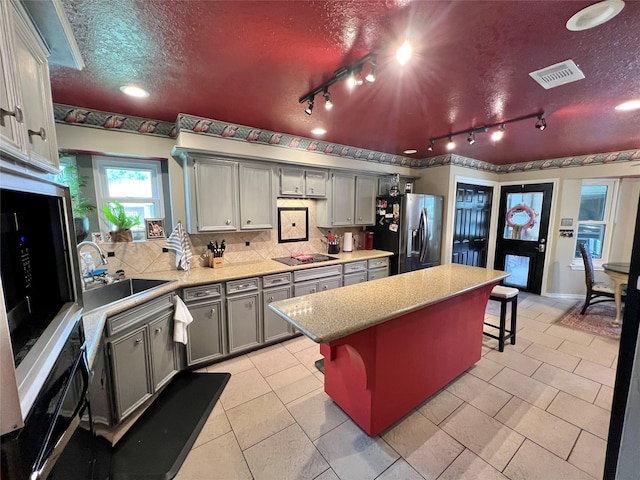 51 S Trillium Ct, Lake Jackson, TX 77566 - kitchen featuring stainless steel refrigerator with ice dispenser, gray cabinets, track lighting, tasteful backsplash, and a kitchen island