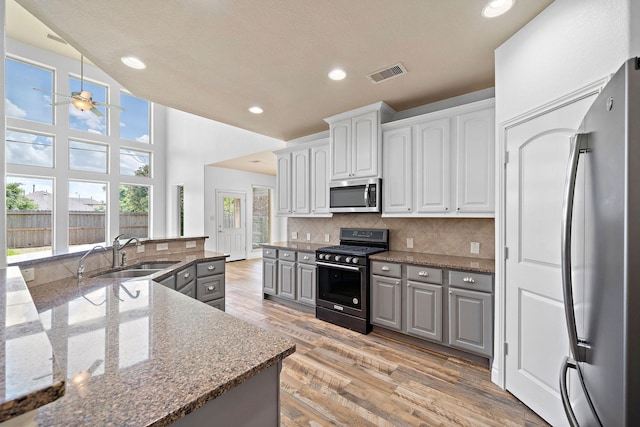 28915 Crested Butte Dr, Katy, TX 77494 - kitchen featuring stainless steel appliances, ceiling fan, tasteful backsplash, dark stone counters, and light wood finished floors