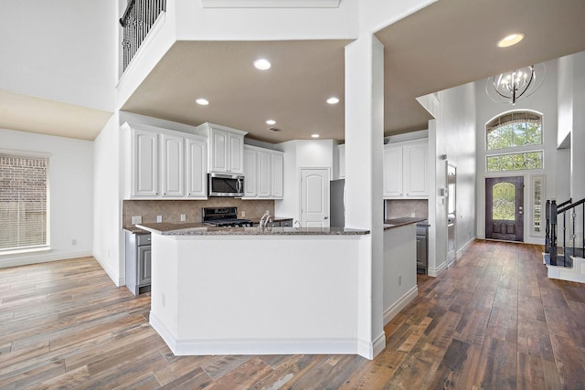 28915 Crested Butte Dr, Katy, TX 77494 - kitchen featuring stainless steel microwave, range, white cabinets, dark wood-type flooring, and a high ceiling