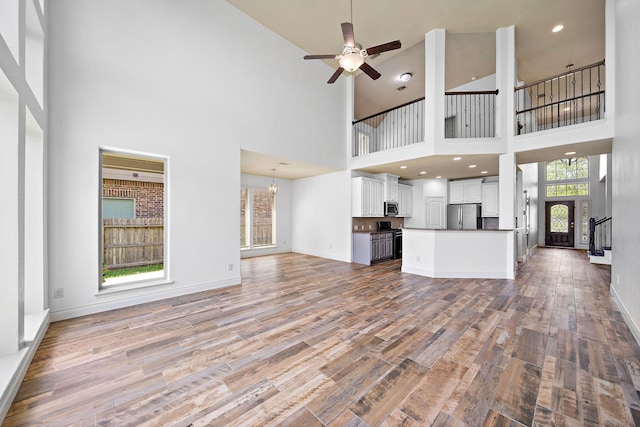 28915 Crested Butte Dr, Katy, TX 77494 - unfurnished living room featuring wood finished floors, a towering ceiling, and ceiling fan