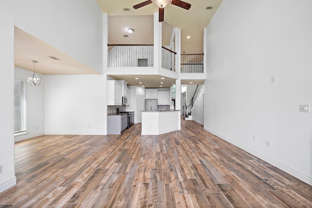 28915 Crested Butte Dr, Katy, TX 77494 - unfurnished living room featuring ceiling fan, wood finished floors, a towering ceiling, stairs, and a chandelier