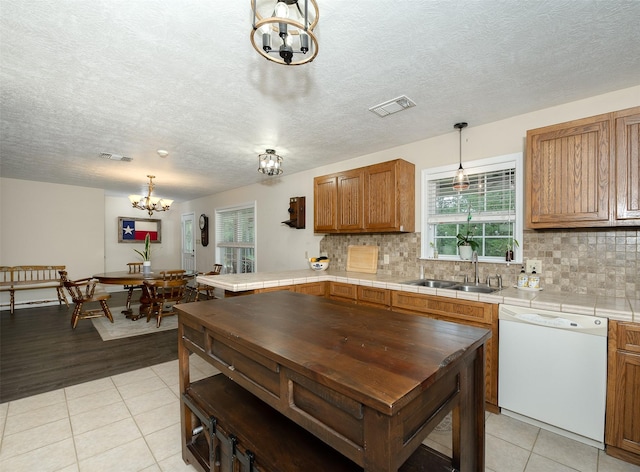 505 Sage Brush Dr, Somerville, TX 77879 - kitchen with white dishwasher, a chandelier, tasteful backsplash, light tile patterned floors, and a textured ceiling