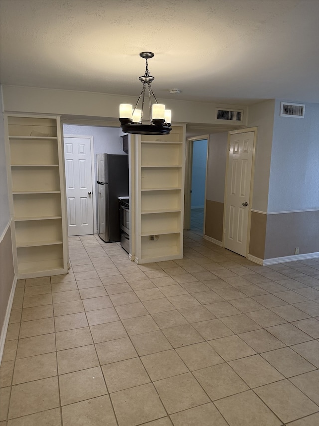 7555 Katy Fwy Unit 57, Houston, TX 77024 - unfurnished dining area featuring a chandelier, built in shelves, and light tile patterned flooring