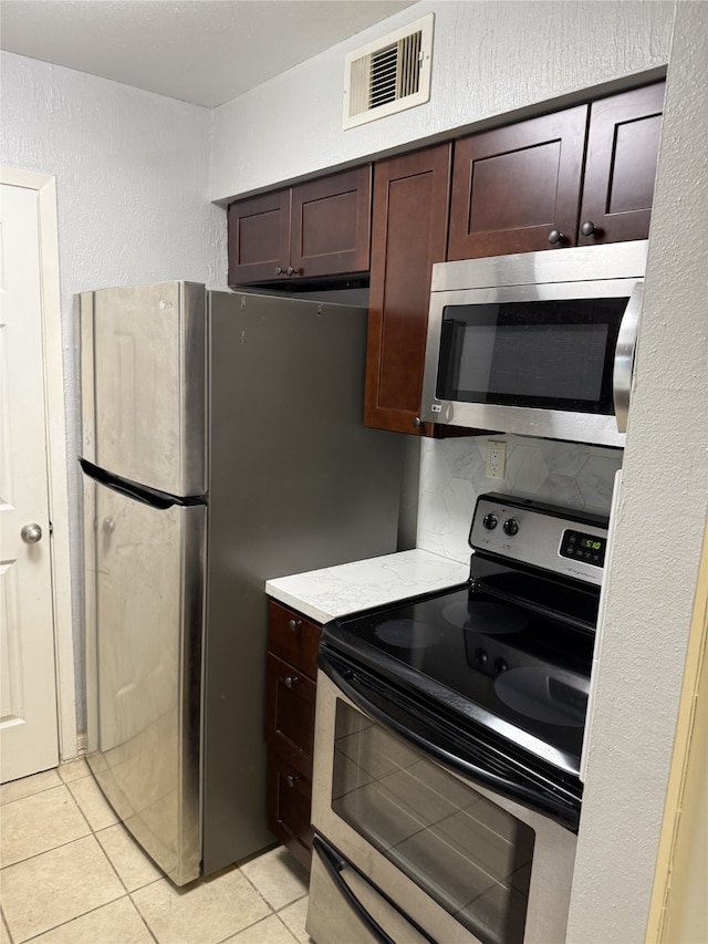 7555 Katy Fwy Unit 57, Houston, TX 77024 - kitchen featuring appliances with stainless steel finishes, light tile patterned floors, light countertops, and dark brown cabinets