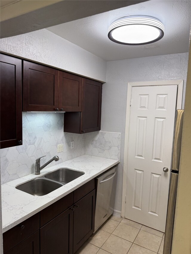 7555 Katy Fwy Unit 57, Houston, TX 77024 - kitchen featuring appliances with stainless steel finishes, backsplash, light tile patterned flooring, dark brown cabinets, and a textured wall