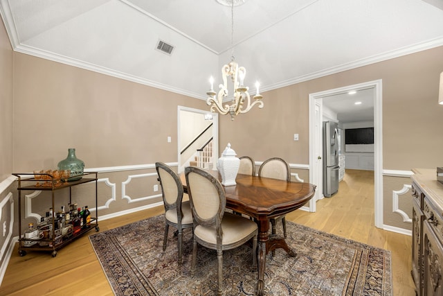 9727 Godstone Ln, Spring, TX 77379 - dining space featuring light wood-style flooring, crown molding, a wainscoted wall, stairway, and a chandelier