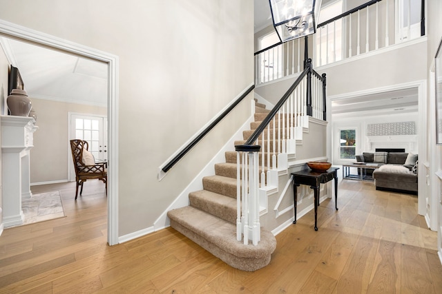 9727 Godstone Ln, Spring, TX 77379 - staircase with wood-type flooring, a fireplace, a high ceiling, and crown molding