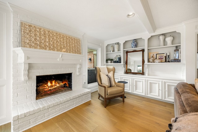 9727 Godstone Ln, Spring, TX 77379 - sitting room featuring a brick fireplace, light wood-style flooring, built in shelves, and crown molding