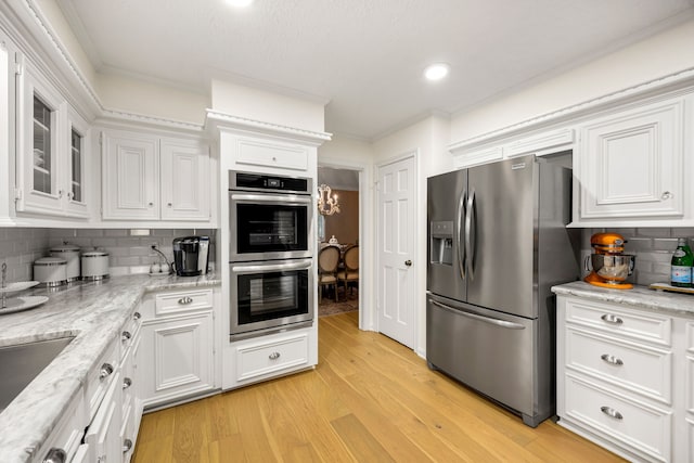 9727 Godstone Ln, Spring, TX 77379 - kitchen with appliances with stainless steel finishes, crown molding, white cabinets, tasteful backsplash, and light wood-style flooring