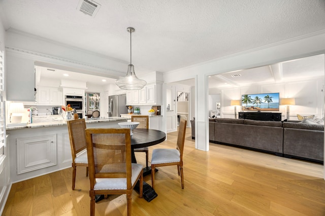 9727 Godstone Ln, Spring, TX 77379 - dining room featuring light wood-style floors, ornamental molding, recessed lighting, a textured ceiling, and beam ceiling