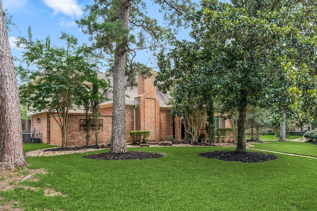 9727 Godstone Ln, Spring, TX 77379 - view of property hidden behind natural elements featuring a front yard, brick siding, a shingled roof, and a chimney