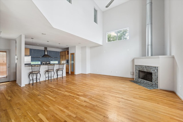 5219 Kiam St Unit F, Houston, TX 77007 - living room with light wood-type flooring, a high ceiling, a fireplace, and a ceiling fan