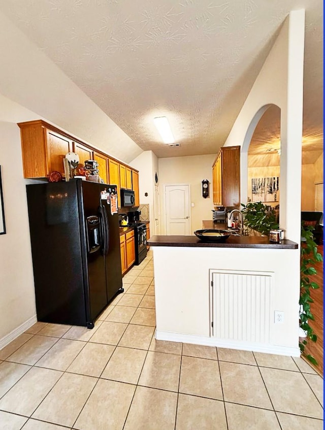 8010 N Tarrytown Crossing Dr, Conroe, TX 77304 - kitchen featuring black appliances, a textured ceiling, dark countertops, brown cabinets, and vaulted ceiling