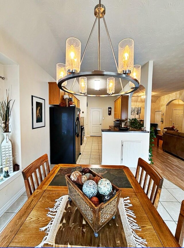8010 N Tarrytown Crossing Dr, Conroe, TX 77304 - dining area featuring light tile patterned floors, a chandelier, and arched walkways