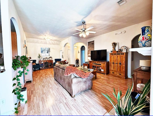 8010 N Tarrytown Crossing Dr, Conroe, TX 77304 - living room featuring arched walkways, a ceiling fan, light wood finished floors, and a textured ceiling