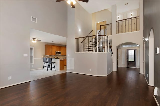 216 Willow Pointe Dr, League City, TX 77573 - unfurnished living room with a ceiling fan, a towering ceiling, wood finished floors, stairs, and arched walkways