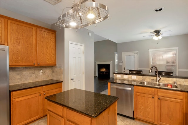 216 Willow Pointe Dr, League City, TX 77573 - kitchen with appliances with stainless steel finishes, a warm lit fireplace, ceiling fan, tasteful backsplash, and dark stone countertops