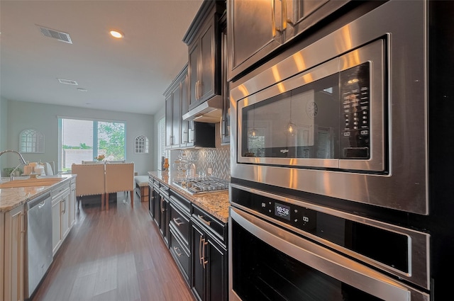 11527 Taagan Ln, Richmond, TX 77407 - kitchen featuring appliances with stainless steel finishes, wood finished floors, light stone counters, recessed lighting, and tasteful backsplash
