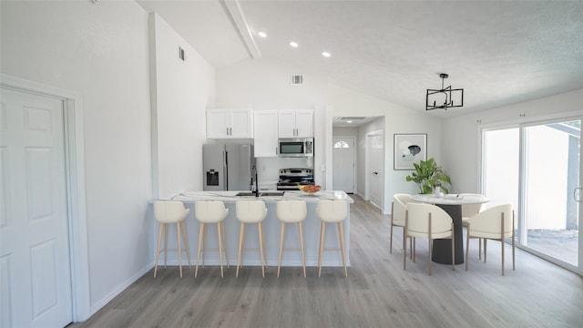 14223 Edenglen Dr, Houston, TX 77049 - kitchen featuring appliances with stainless steel finishes, light wood-style floors, a breakfast bar, white cabinets, and a chandelier