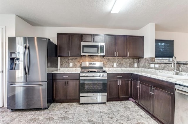 19346 Bold River Rd, Tomball, TX 77375 - kitchen with appliances with stainless steel finishes, dark brown cabinets, tasteful backsplash, and a textured ceiling
