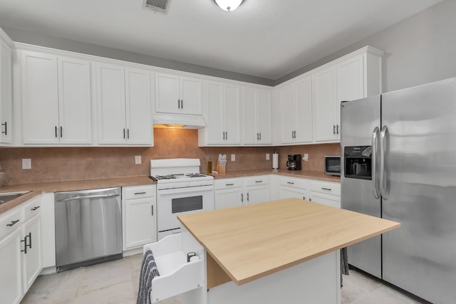5822 Santa Bernadetta, Houston, TX 77017 - kitchen with appliances with stainless steel finishes, under cabinet range hood, white cabinetry, a kitchen bar, and butcher block counters