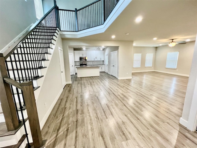 4301 Clover St, Houston, TX 77051 - unfurnished living room featuring light wood-type flooring, stairway, ceiling fan, recessed lighting, and a high ceiling