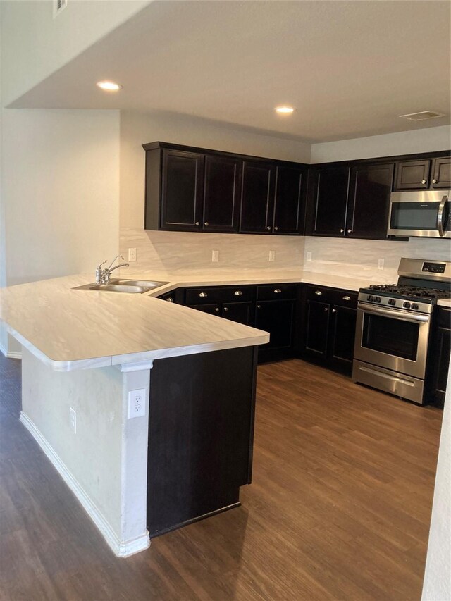 15443 Cipres Verde St, Channelview, TX 77530 - kitchen featuring appliances with stainless steel finishes, dark wood-style flooring, a peninsula, light countertops, and recessed lighting