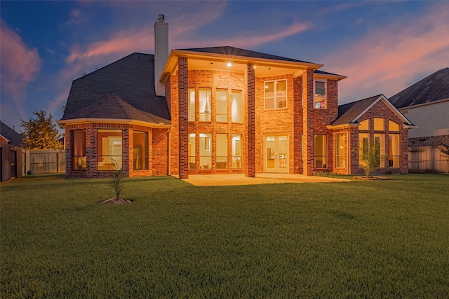 8707 Crossriver Ln, Houston, TX 77095 - back of property at dusk featuring brick siding, a chimney, a fenced backyard, and a patio