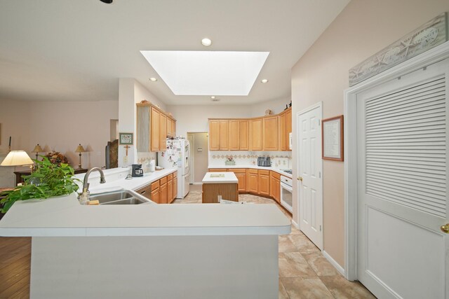 1512 Pine Ridge Ln, Pearland, TX 77581 - kitchen with white refrigerator with ice dispenser, a skylight, a peninsula, light countertops, and light brown cabinetry