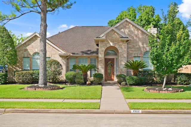 1512 Pine Ridge Ln, Pearland, TX 77581 - view of front of property with brick siding, a front yard, a chimney, and roof with shingles