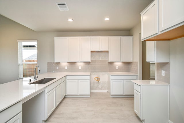 11110 Crocus Dr, Houston, TX 77044 - kitchen with light wood-type flooring, decorative backsplash, white cabinetry, recessed lighting, and light countertops