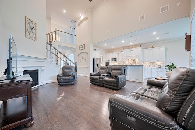 19415 Maifest Dr, Cypress, TX 77433 - living room featuring dark wood-style flooring, a high ceiling, a fireplace, ornamental molding, and recessed lighting