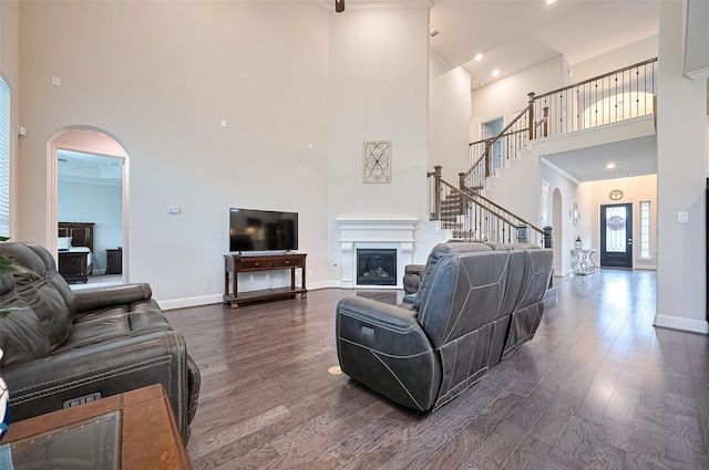 19415 Maifest Dr, Cypress, TX 77433 - living area featuring a towering ceiling, arched walkways, dark wood-style flooring, a fireplace, and stairway