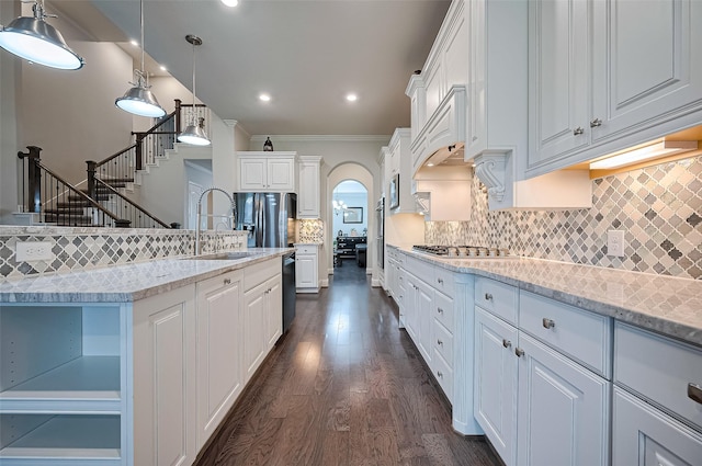19415 Maifest Dr, Cypress, TX 77433 - kitchen with arched walkways, dark wood finished floors, ornamental molding, white cabinetry, and tasteful backsplash